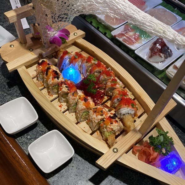 Saisaki Van Wert sushi rolls, garnished with roe and sauce, served on a decorative wooden boat.