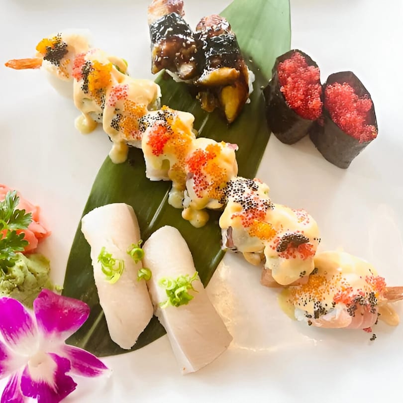 A vibrant Saisaki sushi platter with various rolls, nigiri, and a purple orchid garnish.
