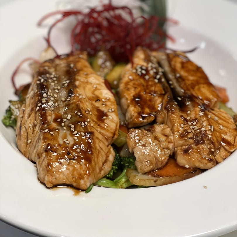 Saisaki Van Wert's teriyaki salmon with sesame seeds, served over mixed vegetables and red garnish.
