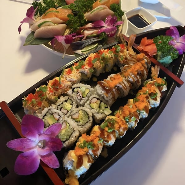 A boat-shaped platter of Saisaki sushi rolls and a plate of sashimi with orchids.